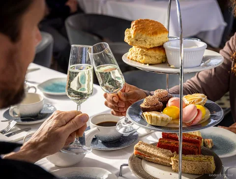 Gäster sittande vid ett bord på en afternoon tea kryssning på Themsen med utsikt över floden