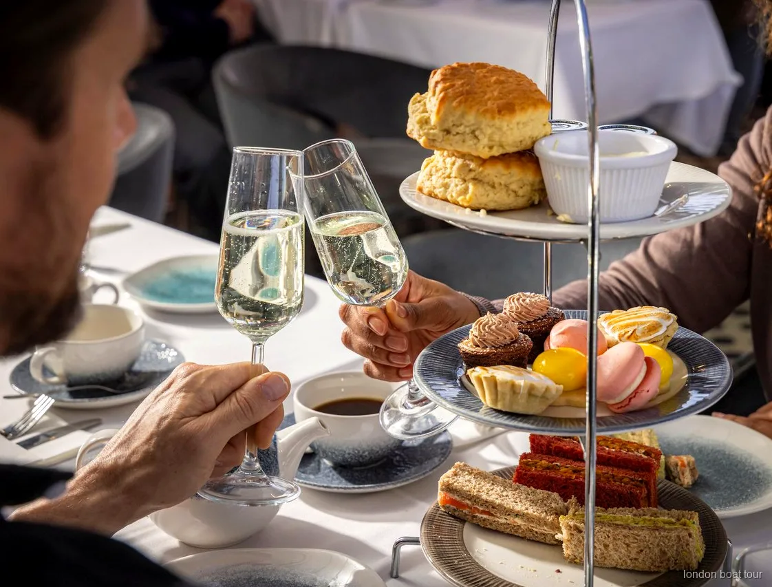 Gäster sittande vid ett bord på en afternoon tea kryssning på Themsen med utsikt över floden