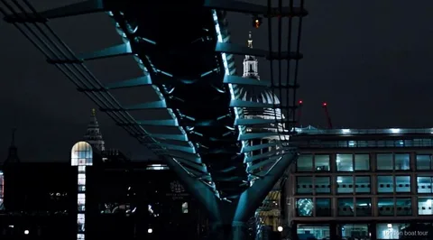 Passatgers en un vaixell de creuer nocturn passant per un pont il·luminat del Tàmesi