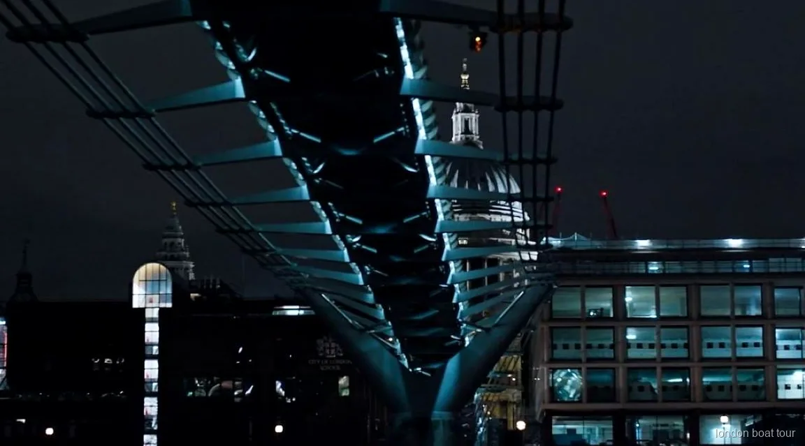 Passatgers en un vaixell de creuer nocturn passant per un pont il·luminat del Tàmesi