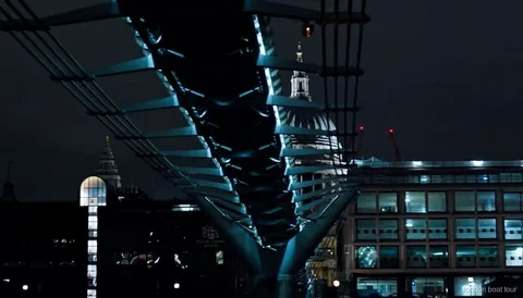 Passeggeri su una crociera notturna illuminata che passano davanti a un ponte illuminato sul Tamigi