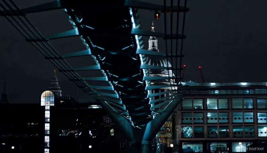 Passeggeri su una crociera notturna illuminata che passano davanti a un ponte illuminato sul Tamigi
