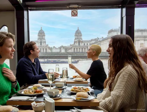 Invitados comiendo junto a una ventana en un crucero con almuerzo por el río Támesis