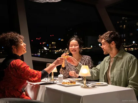 Mesa preparada para una cena de 3 platos en un crucero por el Támesis de noche