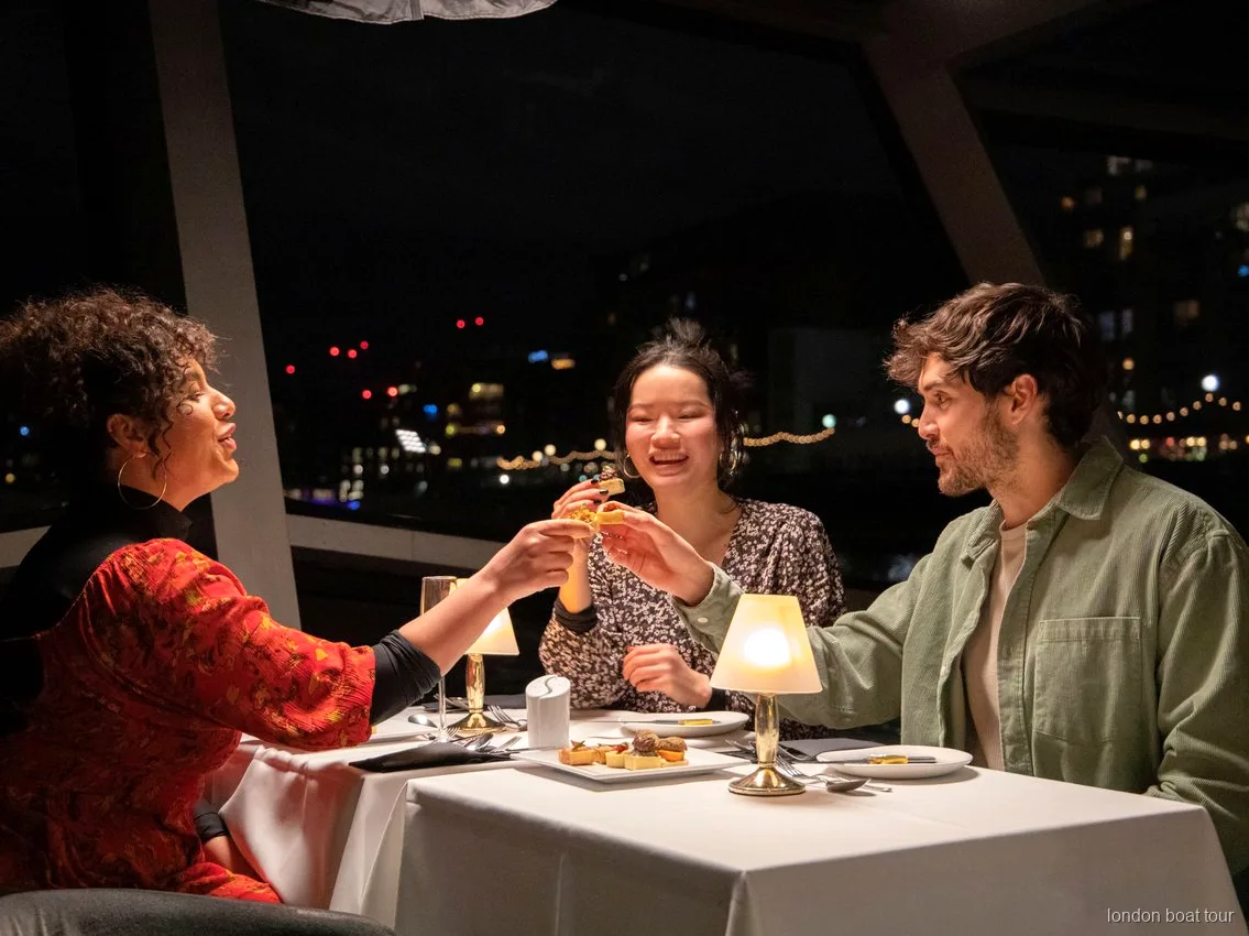 Mesa preparada para una cena de 3 platos en un crucero por el Támesis de noche