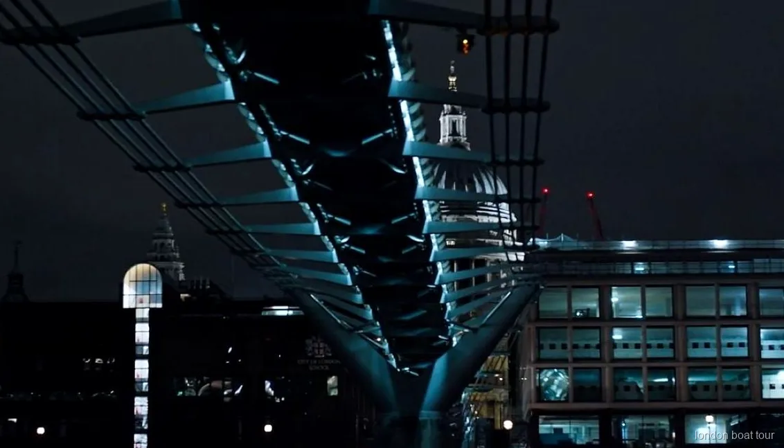 Pasajeros en un crucero nocturno pasando junto a un puente iluminado del Támesis