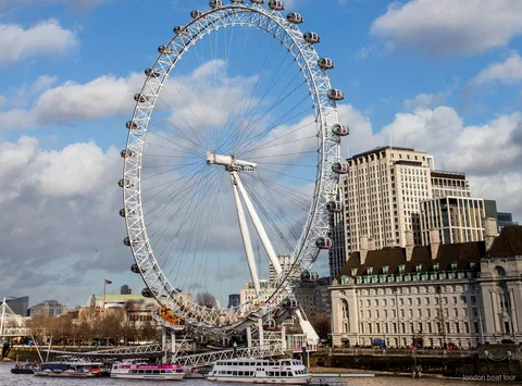 Tower Bridge'in önünden geçen London Eye nehir turu teknesindeki yolcular