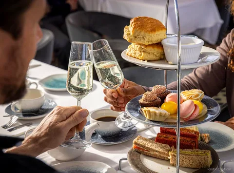 Guests seated at a table on a Thames afternoon tea cruise boat with river views
