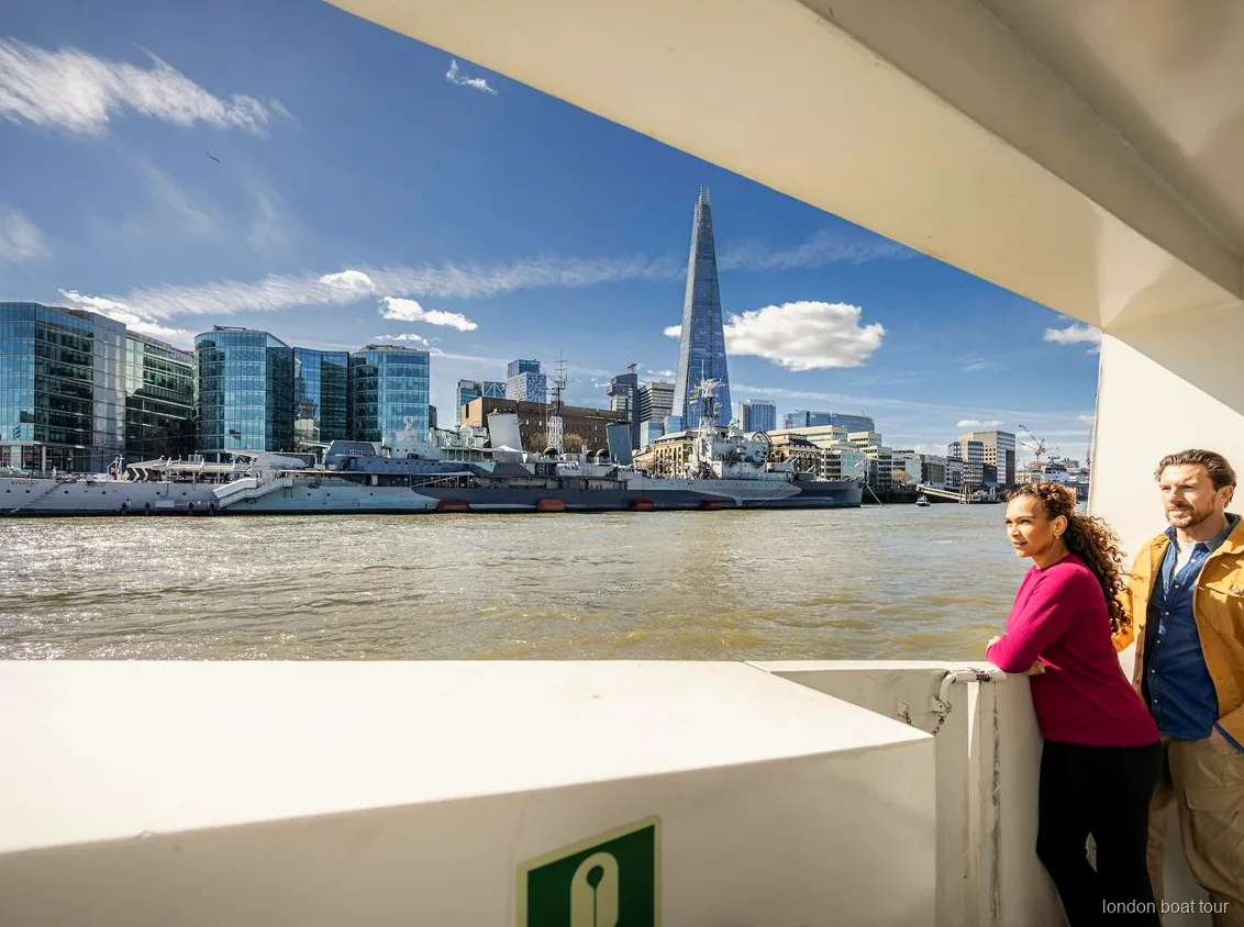 Open deck seating on a Thames hop-on hop-off sightseeing cruise with London landmarks behind