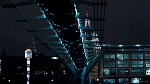 Işıklı bir Thames köprüsünün önünden geçen gece turu teknesindeki yolcular