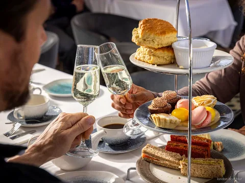 Gasten aan een tafel op een afternoon tea cruise boot met uitzicht op de rivier