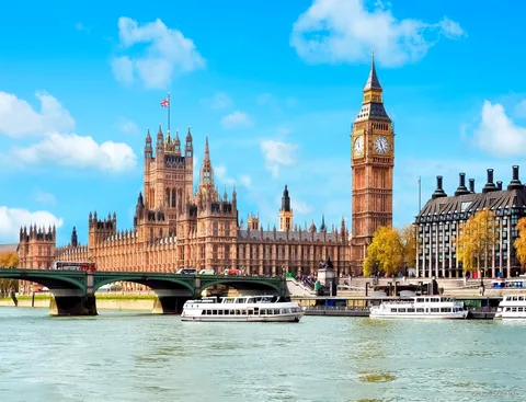 Passagiers op het open dek van een Theems boottocht met de skyline van Londen op de achtergrond